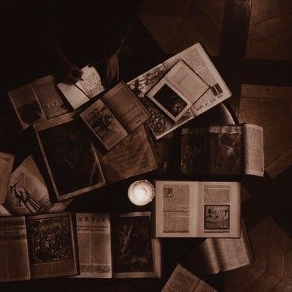 an overhead view of several open books on a table with a candle and some pictures