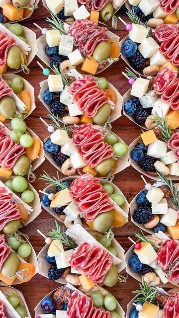 an assortment of appetizers are arranged on small trays with fruit and cheese