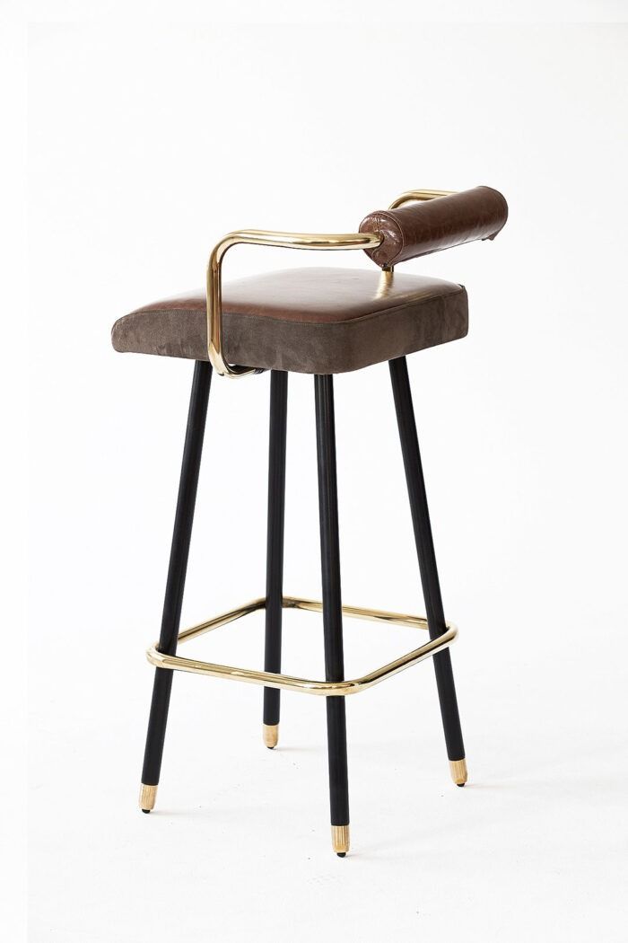 an upholstered bar stool with a leather seat and metal frame, in front of a white background