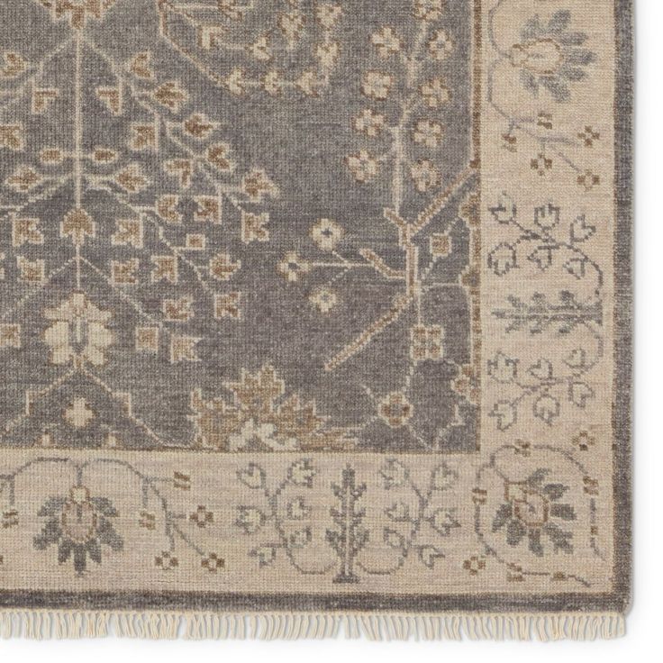 a gray and beige rug with floral designs on the bottom, along with fringes