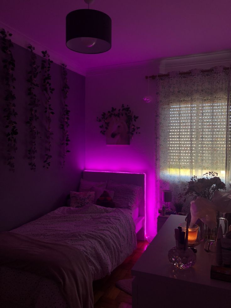 a bedroom with purple lighting and plants on the window sill in front of the bed