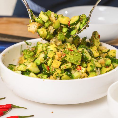 a white bowl filled with cucumber and other food on top of a table