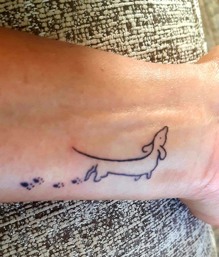 a person with a small tattoo on their wrist that has a dog drawn on it