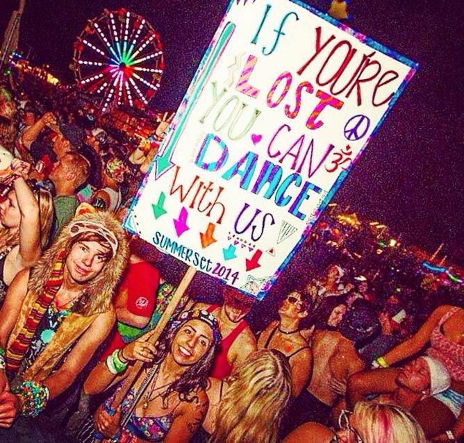 a group of people standing around each other in front of a sign that says if you're lost, you can dance with us