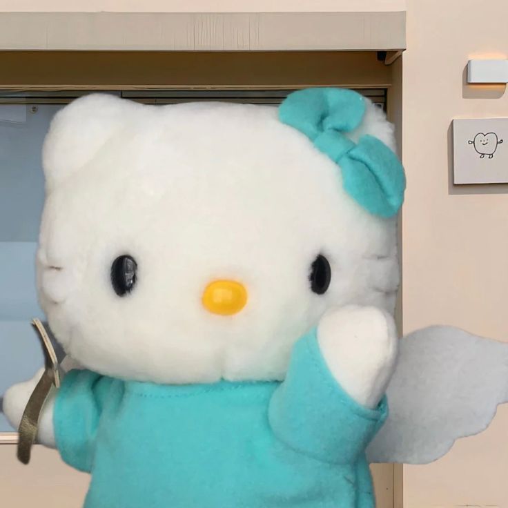 a hello kitty stuffed animal holding a wrench in front of an open door,