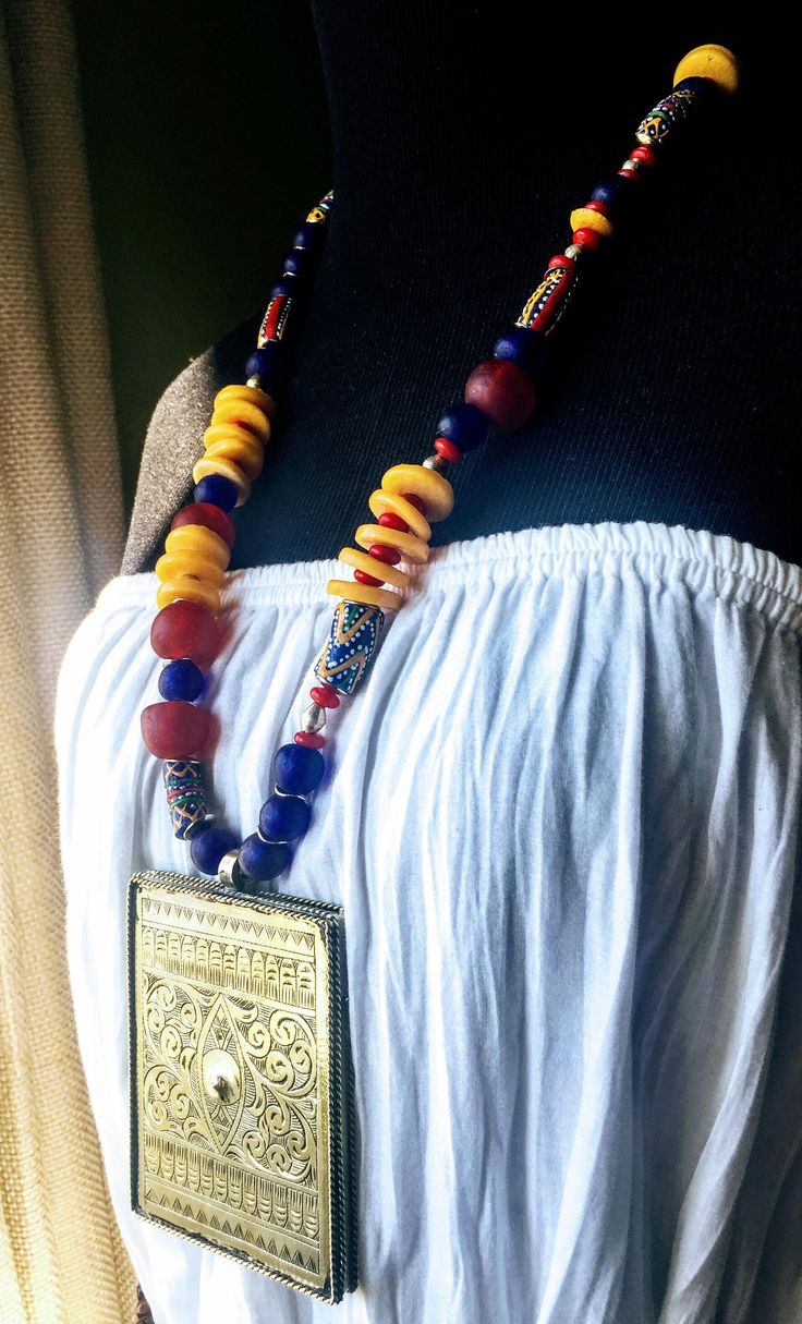 This necklace features a Tuareg style huge vintage Moroccan Pendant strung in a long strand of African Krobo Beads coupled with African recycled glass beads, Ethiopian tribal bi-cones in silver and silver plated discs. The vibrant color combination of yellow, red and blue flows in a lovely balance across the different styles of Krobo beads used in this necklace. At every angle this necklace looks breathtakingly beautiful and makes a striking statement piece! The necklace measures 29 inches from end to end with the 3 inch wide pendant adding an additional 4 inch hanging depth. The pendant is hollow inside. Free shipping within US. --- African Necklace Tribal Fusion Bohemian Ethnic Necklace Silver Necklace Tribal Necklace Boho Necklace Colorful Necklace Tuareg Long Necklace Traditional Long Necklace For Beach, Multicolor Necklaces With Large Beads For Rituals, Multicolor Large Beads Necklace For Rituals, Traditional One-of-a-kind Multicolor Beaded Necklace, Eclectic Festival Necklaces With Large Beads, Traditional Multicolor Beaded Necklace With Large Pendant, Multicolor Bohemian Long Necklace With Polished Beads, Bohemian Long Necklace For Festivals, Bohemian Multicolor Long Necklace For Festivals