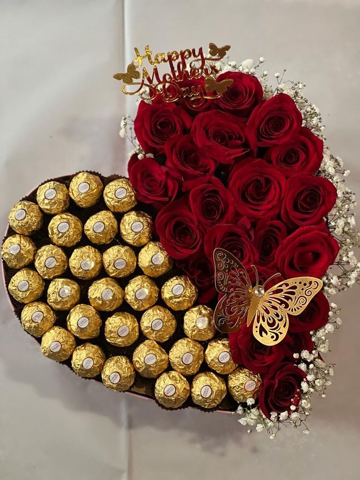 a heart shaped box filled with red roses and chocolates in the shape of a heart