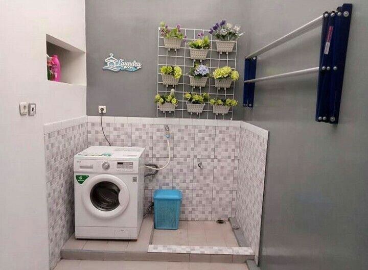 a washer and dryer in a small room with tile flooring on the walls