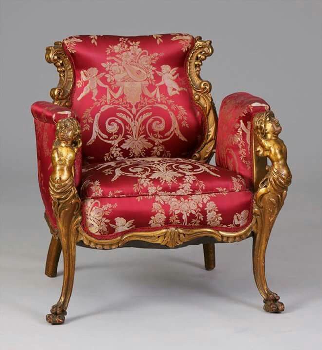 an ornately decorated red chair with gold trimming on the armrests and back