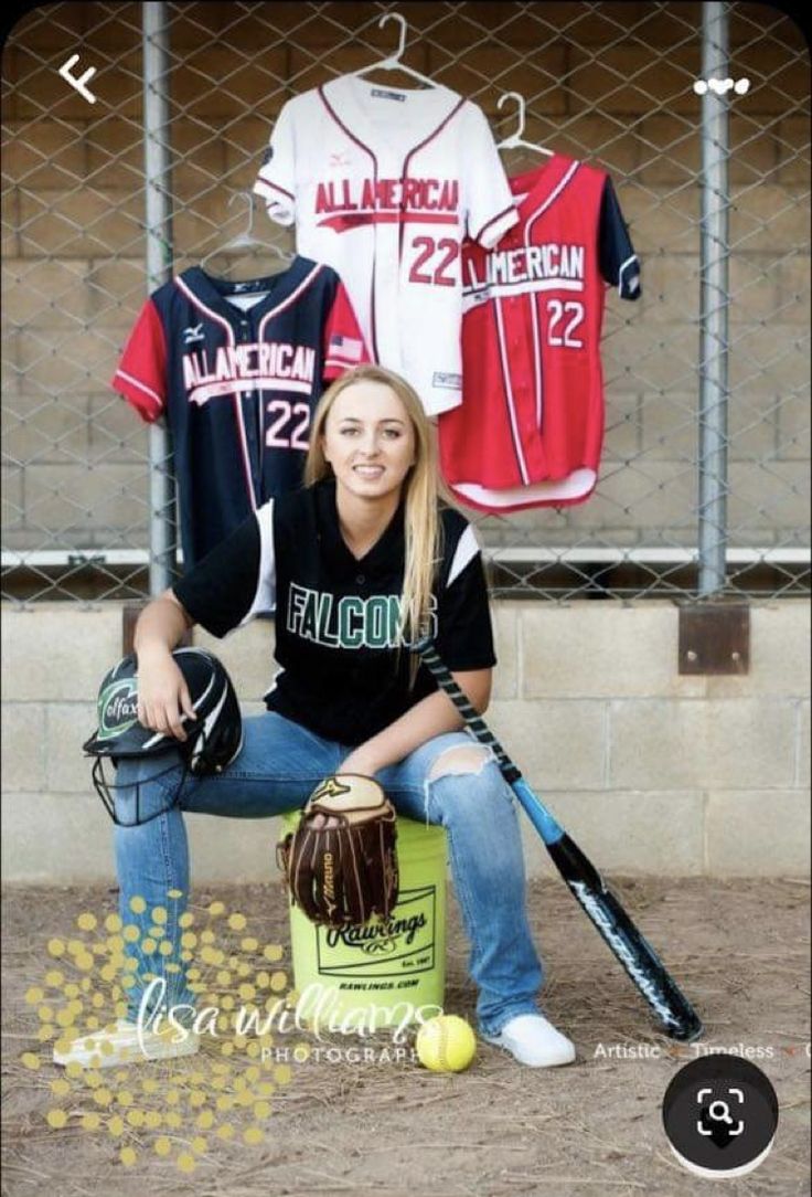 a woman kneeling down next to a baseball bat and ball in front of some t - shirts