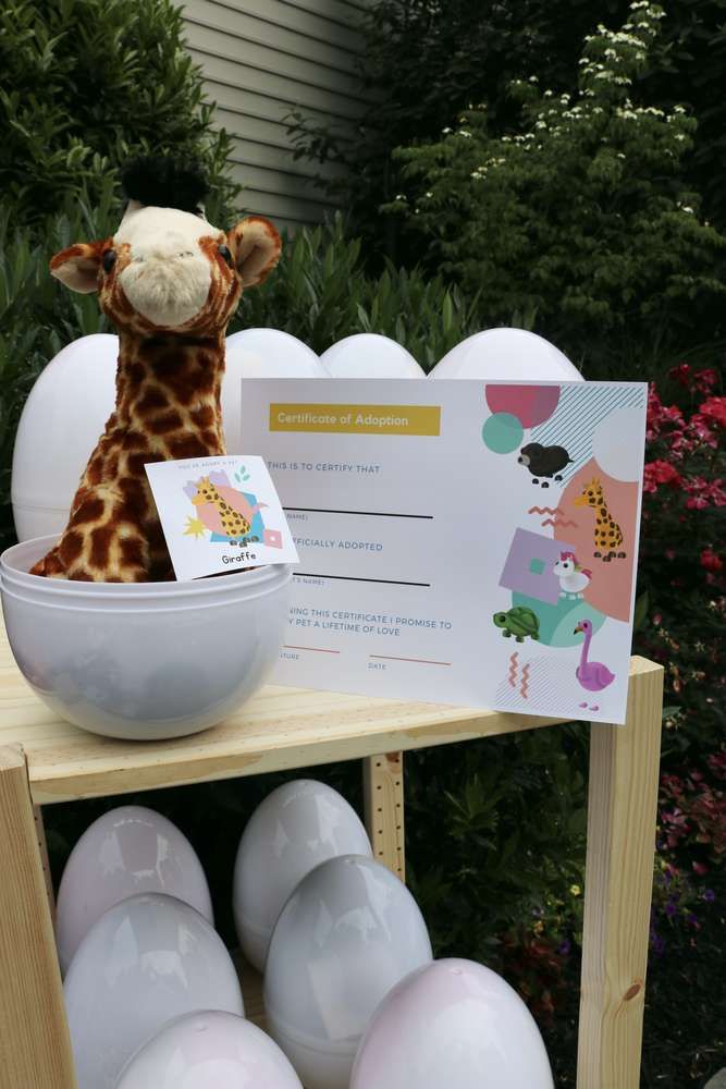 a stuffed giraffe sitting on top of a table next to balloons and a sign