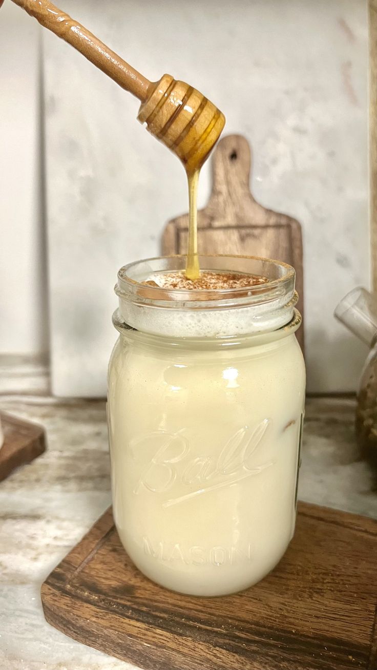 a jar filled with honey sitting on top of a wooden cutting board