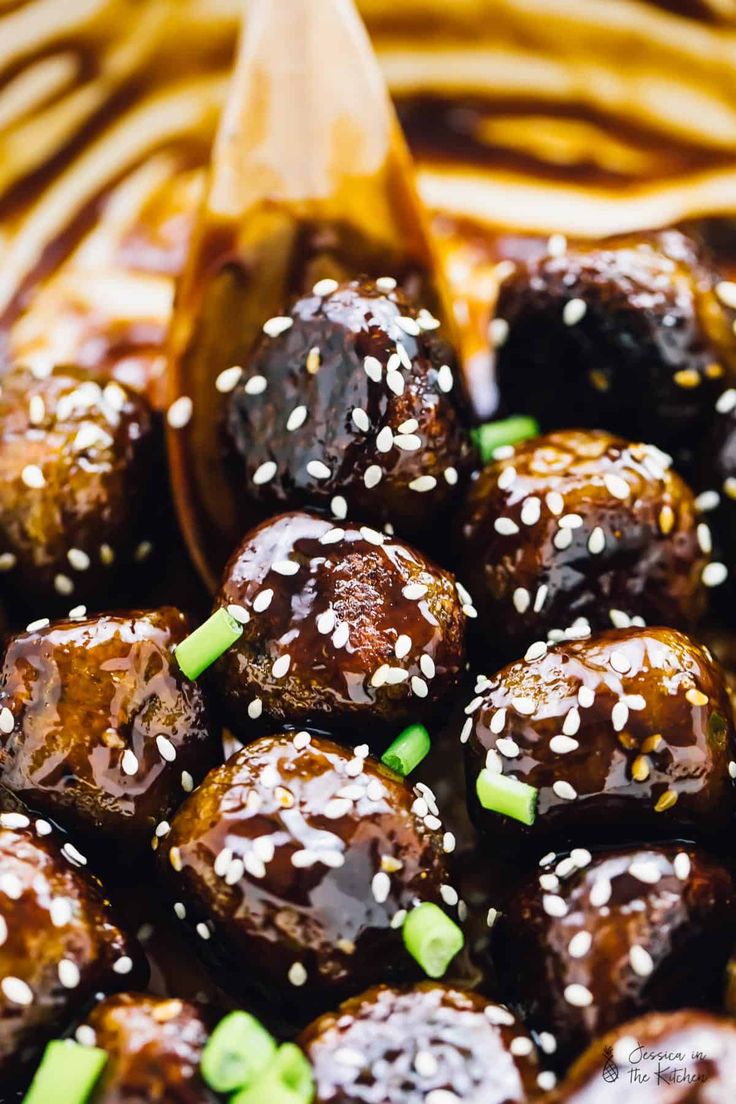 sesame seed meatballs in a brown sauce with green onions and sesame seeds on top