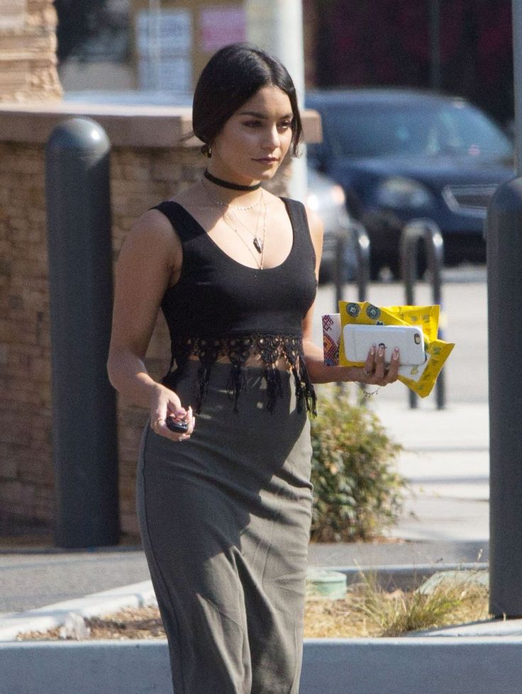 a woman is walking down the street with a box in her hand and looking at something