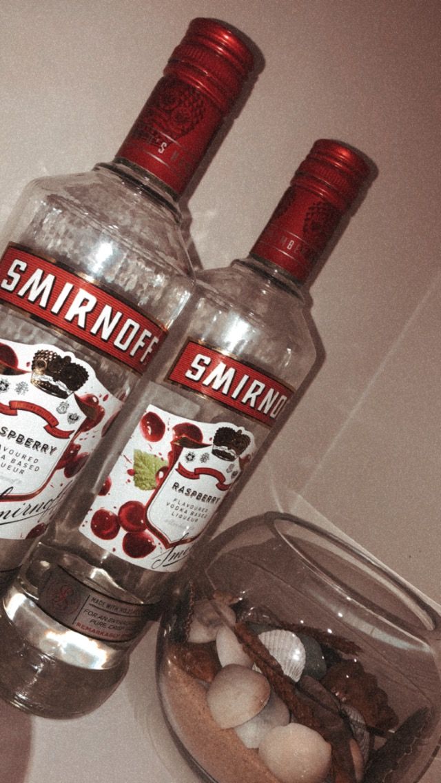 two bottles of smirnoff vodka sitting on top of a counter next to rocks