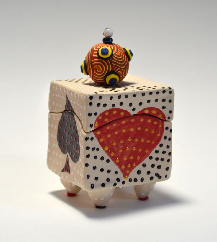 a ceramic box with a red heart on it's lid and an acorn in the middle