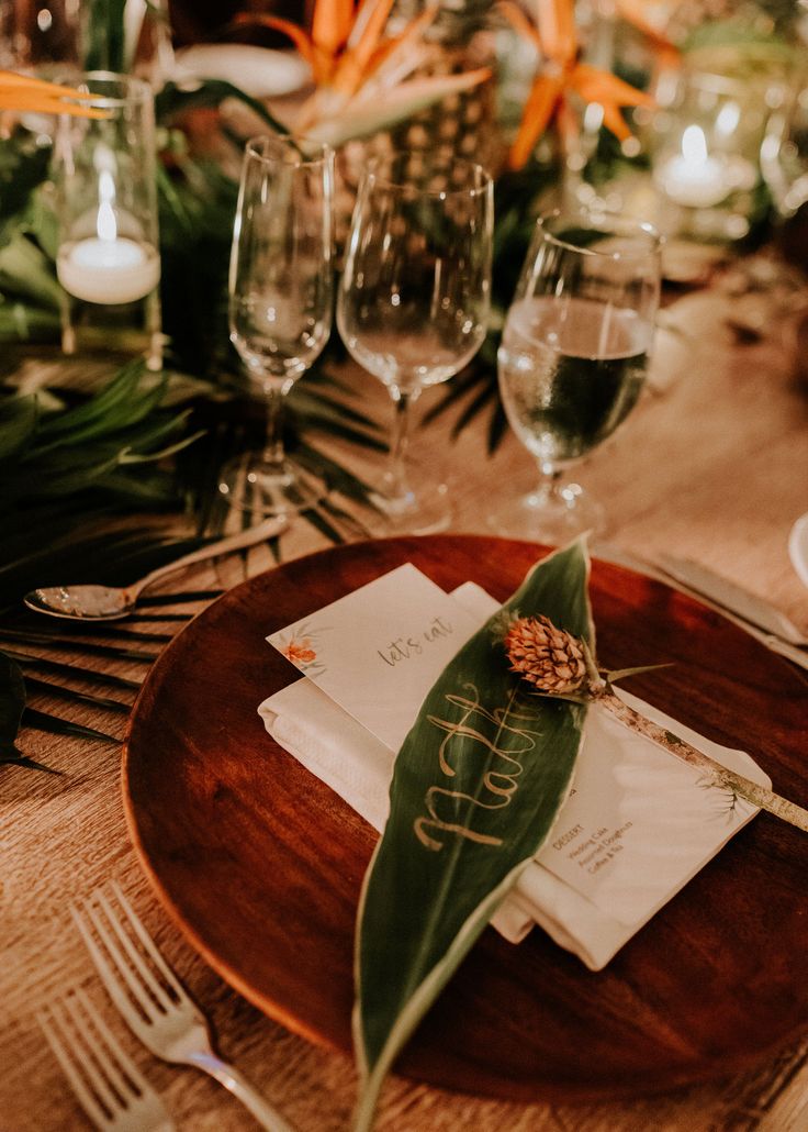 a wooden plate topped with a leaf next to wine glasses