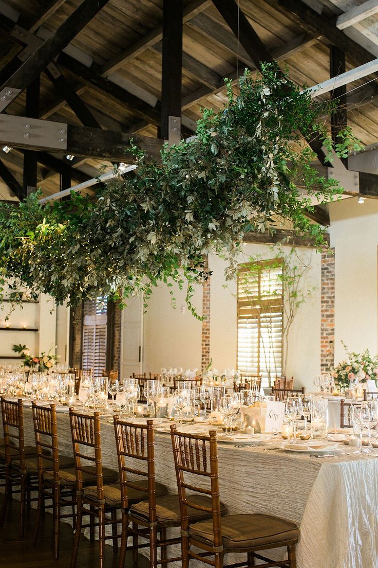 a long table with white linens and greenery is set up for an event