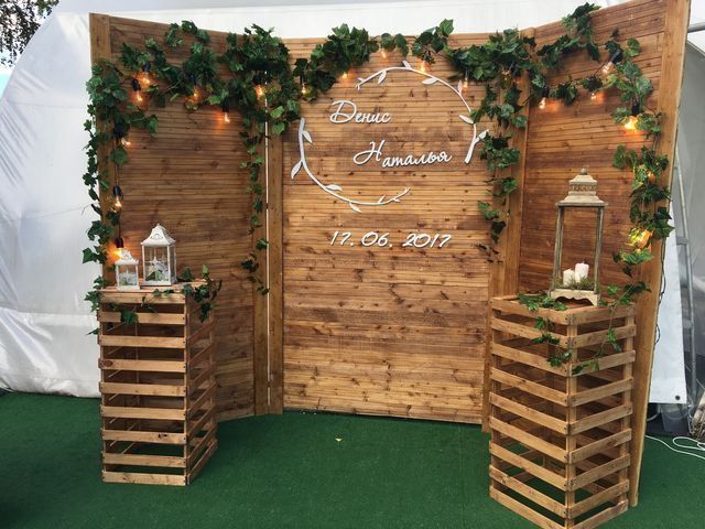 an outdoor wedding setup with wooden crates and greenery on the wall, surrounded by lights