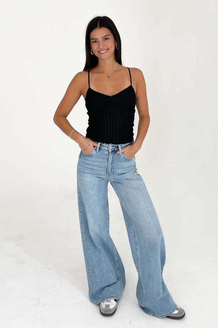 a woman is posing for the camera with her hands on her hips and wearing high rise jeans