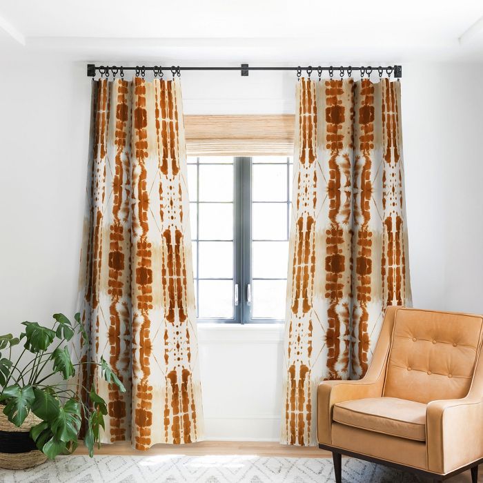 an orange chair sitting in front of a window next to a potted green plant