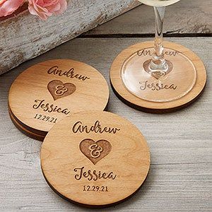 three personalized wooden coasters with wine glasses and flowers in front of them on a table