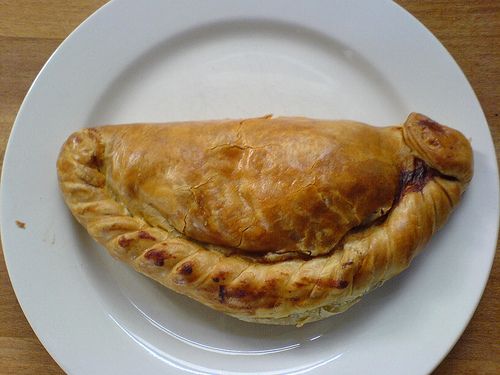 a croissant on a white plate sitting on a wooden table