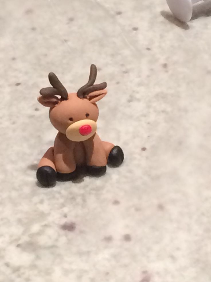 a toy reindeer sitting on the ground next to a white ball