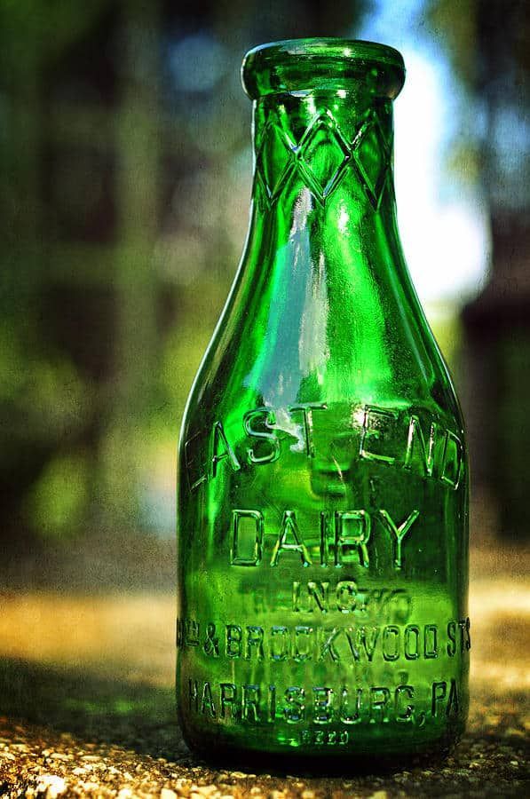 a green glass bottle sitting on the ground