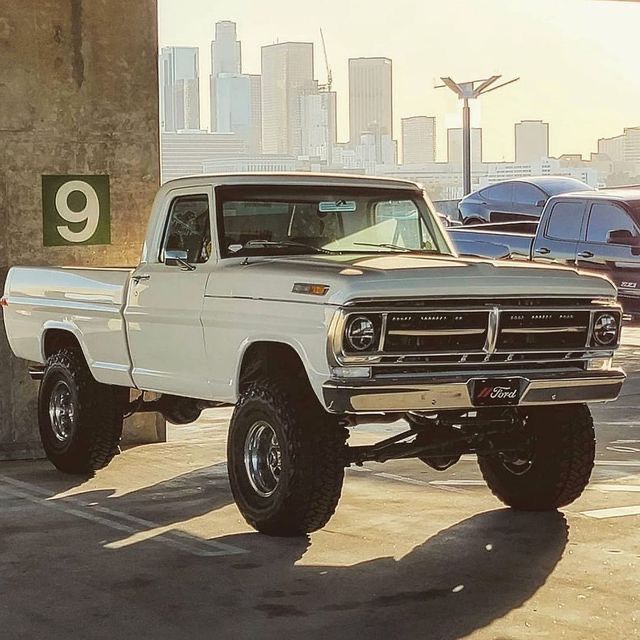 a white pickup truck parked in a parking lot next to a tall building with the number 9 on it