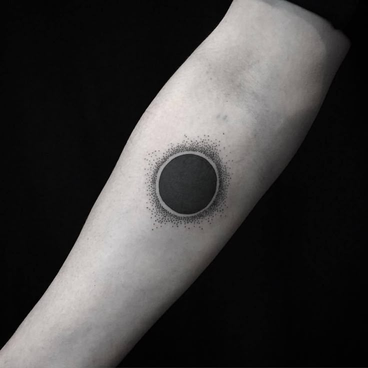 a black and white photo of a person's arm with a circle tattoo on it