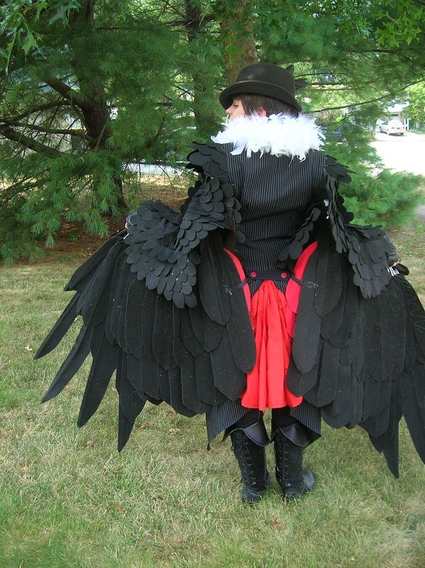 a man dressed in black and red with large wings