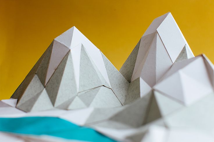 an origami paper mountain is shown against a yellow background