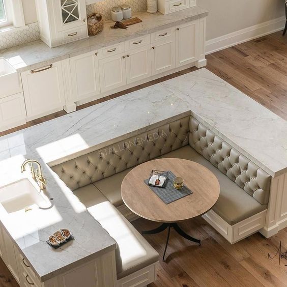 an overhead view of a kitchen with white cabinets and marble countertops, including a corner bench