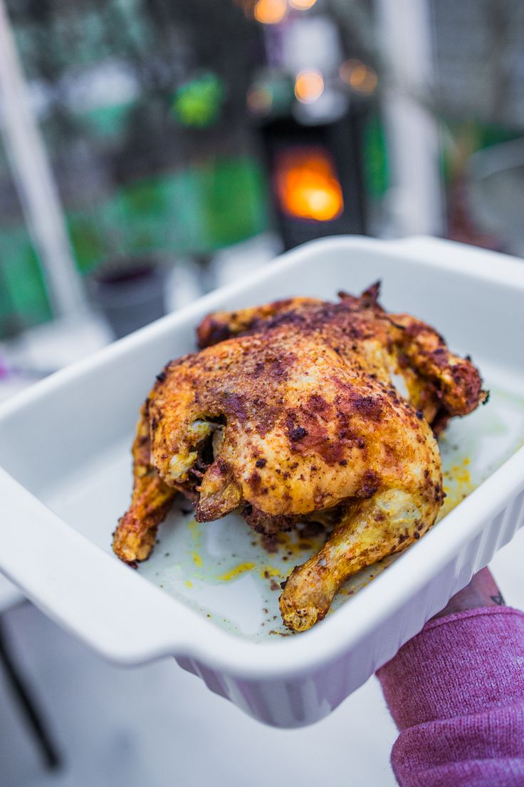 a person holding a white tray with some food in it's hand and the other half eaten chicken sitting on top of it