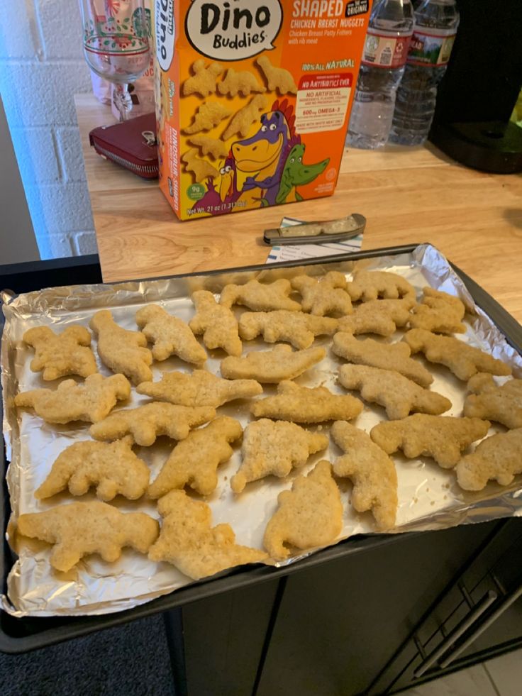 a pan filled with dog biscuits next to a carton of dino crackers