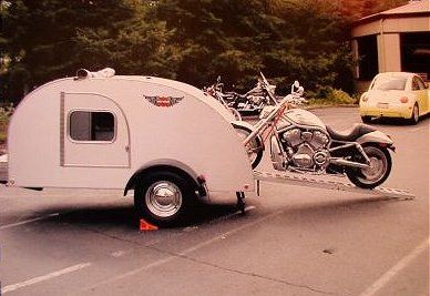 a motor home is parked in the parking lot next to a yellow car and motorcycle