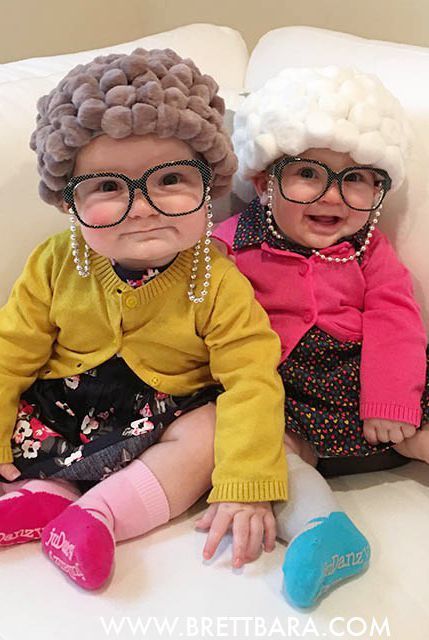 two babies dressed up in wigs and glasses sitting next to each other