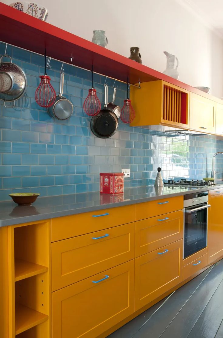 a kitchen with yellow cabinets and blue backsplash