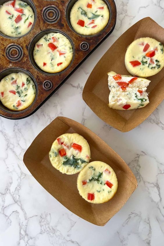 two muffin tins filled with different types of food on top of a table