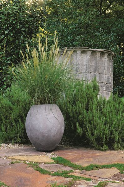 a large gray vase sitting on top of a stone floor next to a planter