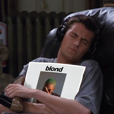 a man laying in a chair holding up a sign with the words blond on it