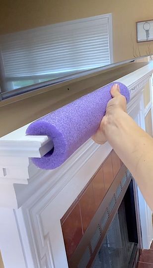 a person holding a purple yoga mat over a fireplace