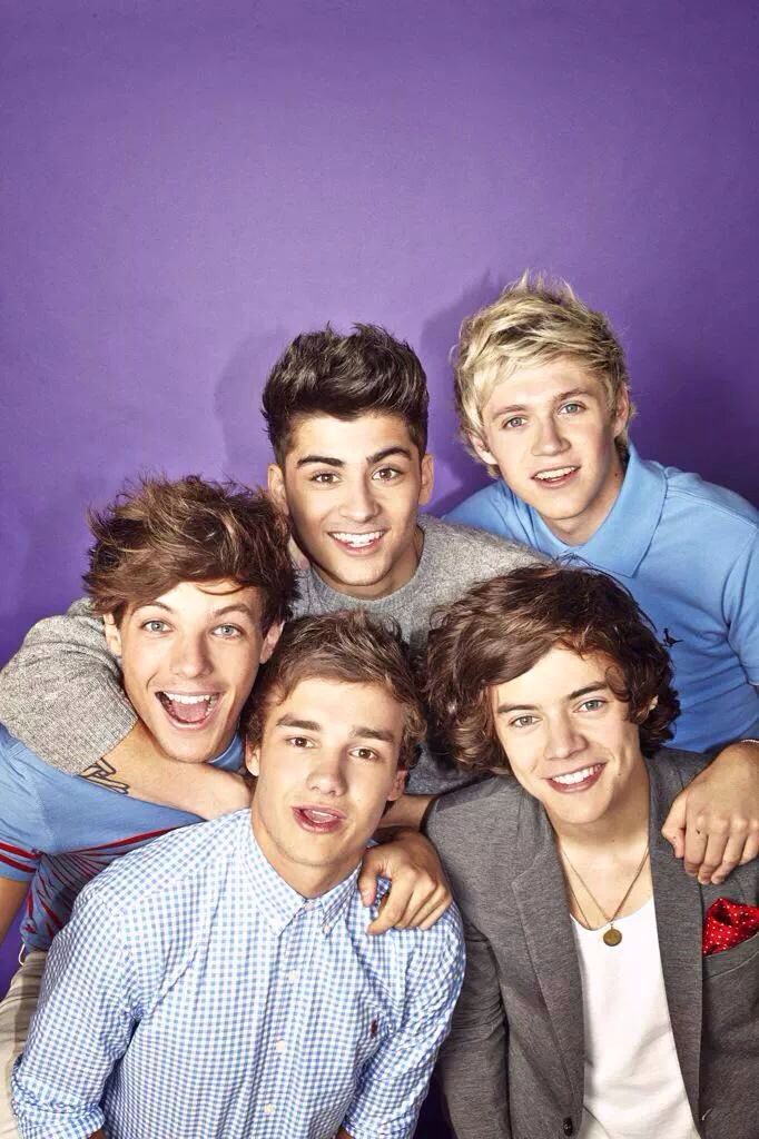 the one direction band is posing for a photo in front of a purple wall with their arms around each other