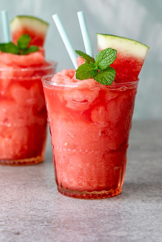 two glasses filled with watermelon and mintade on top of a gray table