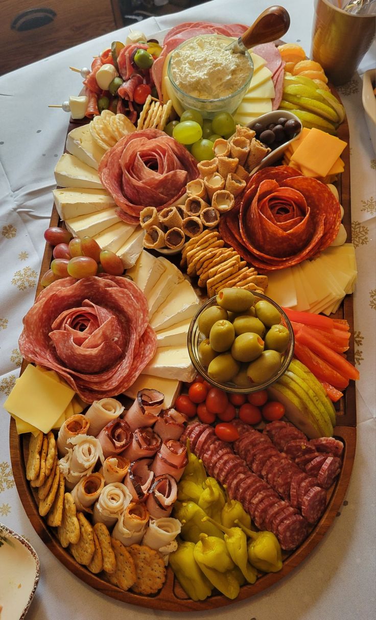 a platter filled with meats, cheeses and other foods on a table