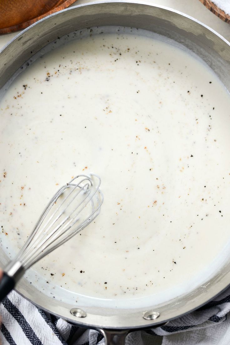 a pan filled with batter and whisk on top of a towel next to a wooden spoon