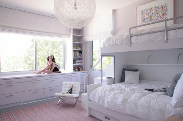 a woman sitting on top of a bed in a bedroom next to a large window