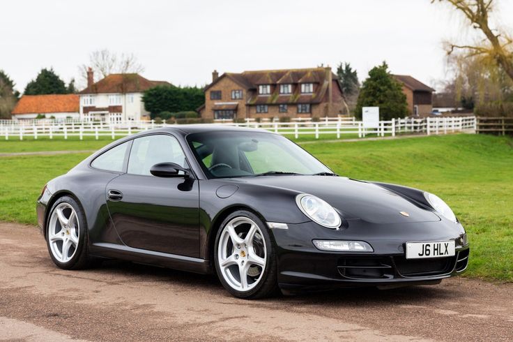 a black sports car parked in front of a fenced in area with houses behind it