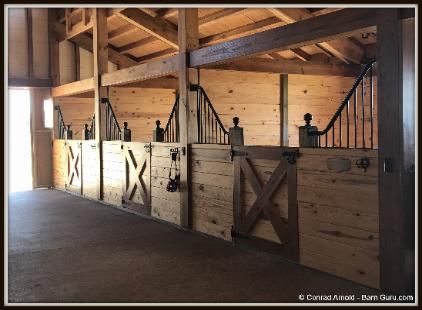 the inside of a horse barn with wooden stalls